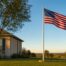 American flag waving on a tall flagpole over a Lubbock Texas front yard at sunset for the 250th Fourth of July, Independence Day