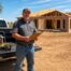West Texas contractor in front of white pickup with open toolbox at Lubbock residential construction site
