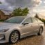Silver sedan parked on a wet West Texas driveway after a hailstorm with hailstones on the pavement and storm clouds breaking into golden light over a Lubbock-area home.