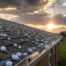 Hailstones scattered across an asphalt-shingle roof of a Texas home with a dented metal gutter and a dramatic storm-aftermath sky.