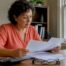 Texas homeowner reads home insurance documents at a desk with a calculator and glasses while reviewing policy endorsements.