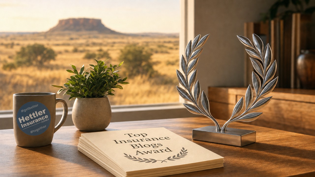 Warm cinematic photograph of a wooden office desk in soft morning light, featuring a plain ceramic coffee mug, a small green potted plant, a neat stack of blank cream-colored papers, and a stylized polished silver laurel-wreath ornament as the focal point, with a blurred West Texas mesa and grassland visible through a large office window in the background.
